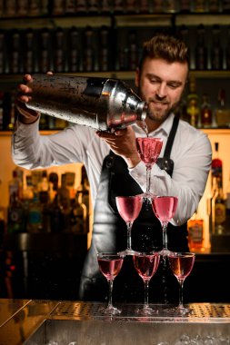 Barmenin büyük bir bardaktan güzel bir kokteyl doldurduğu bardaktan yapılmış kule manzarası