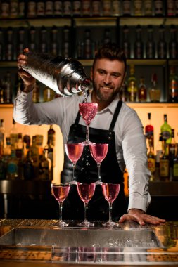 Barmenin büyük bir bardaktan lezzetli bir kokteyl doldurduğu bardaktan yapılmış kule manzarası harika.