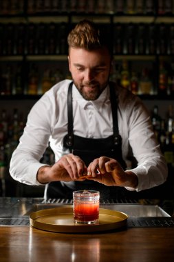 Barmen adam bardaktan narenciye serper bardakta kokteyl, tezgahta da kokteyl.