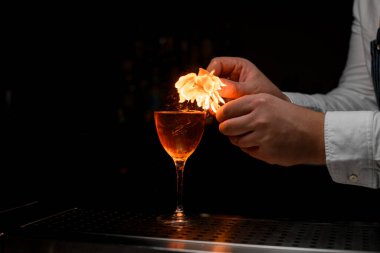 Buzlu bir içecekle şarap bardağının harika manzarası ve barmenin elleri sıçrıyor ve onu ateşe veriyor.