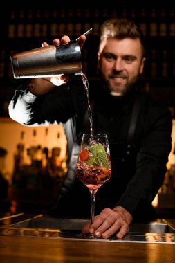 Buzlu çilek ve barmenlerin karıştırıcıdan doğru bir kokteyl doldurduğu naneli bardakla büyüleyici bir manzara.