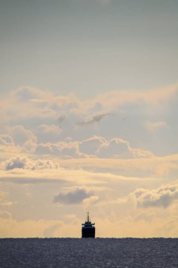 Beyaz bulutlu mavi gökyüzünün muhteşem manzarası ve denizde yelken açan yolcu gemisi.