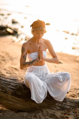 Great close-up view on woman with closed eyes practicing yoga meditate in lotus pose outdoors on beach at morning. Healthy life concept.