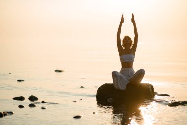 wonderful view on silhouette of beautiful woman practicing yoga in lotus pose sitting on stone. Healthy life concept. Copy space