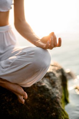 focus on young female hand practicing yoga gyan mudra position, close-up of hands, lotus position.