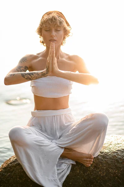 Close-up of beautiful young woman with closed eyes practicing yoga meditate in lotus pose. Healthy life concept.
