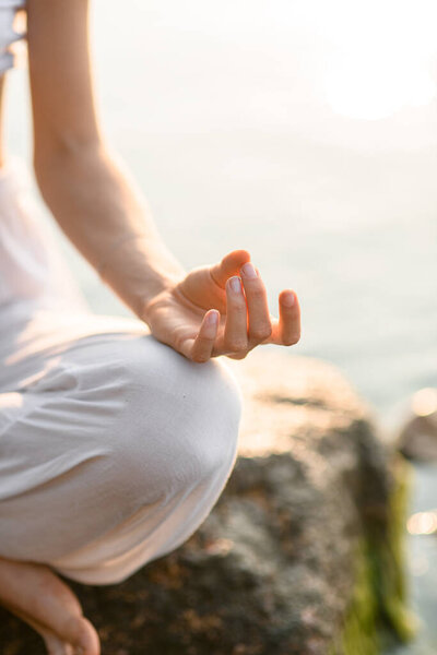 Fragment of young female hand practicing yoga gyan mudra position, close-up of hands, lotus position.