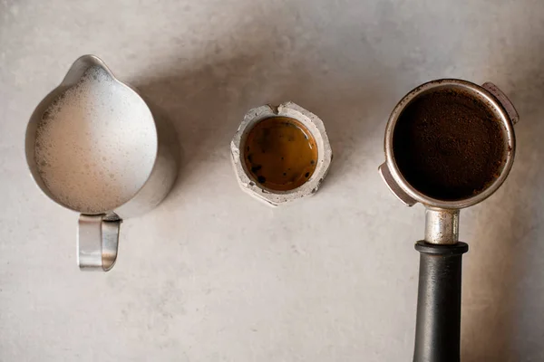 地上コーヒーとコーヒードリンク付きの小さな灰色のカップでいっぱいのポートフィルター付きホルダーのクローズアップトップビュー — ストック写真