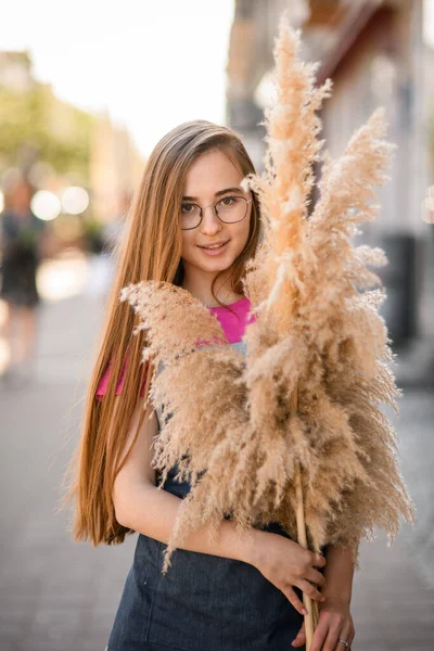 Wanita Muda Cantik Berkacamata Dengan Rambut Panjang Memegang Ranting Rumput Stok Gambar