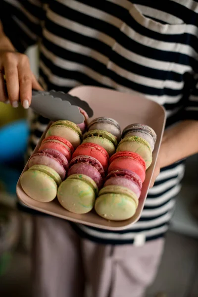 Φρέσκα Γαλλικά Macarons Κέικ Διαφόρων Χρωμάτων Στο Δίσκο Γυναικεία Χέρια — Φωτογραφία Αρχείου