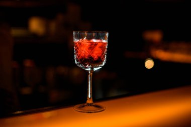 Bar tezgahında kırmızı alkollü içki ve bulanık restoran sahnesi olan kristal kadehin yakın plan perspektifi.