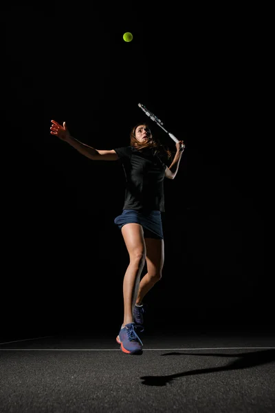 黄色のテニスボールを打つために彼女の手の中にテニスラケットを持つ女性のテニス選手のビュー 暗い背景 スポーツ 健康的なライフスタイルの概念 — ストック写真