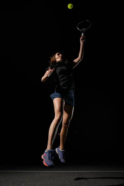 テニスボールを打つために手の中にテニスラケットを持つ運動選手の壮大な景色 暗い背景 スポーツ 健康的なライフスタイルの概念 — ストック写真