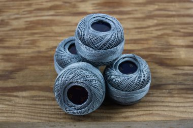 Detail of some balls of dark gray thread with ten grams of quality Perl thread number eight on an old wood