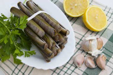 İçinde jilet (ensis) ve limon ve sarımsak bulunan masa aperatif hazırlar.