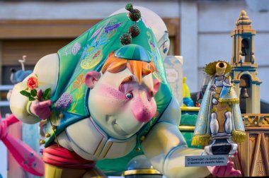 Mart 2019. Valencia, İspanya. Bir yanda Virgen de los Desamparados 'u elinde tutan fallero gibi giyinmiş kambur bir ninotu temsil eden sahne.