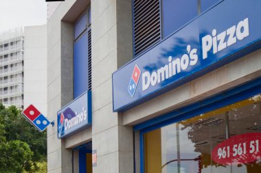 2021 yılı. Valencia, İspanya. Yerel bir Domino 's Pizza şubesinin önünde şirket logoları gösteriliyor.