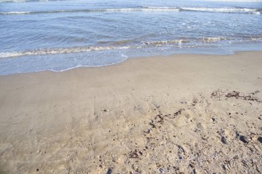 Akdeniz sahilinin arka planında deniz dalgaları olan ilk hattının kum görüntüsü.