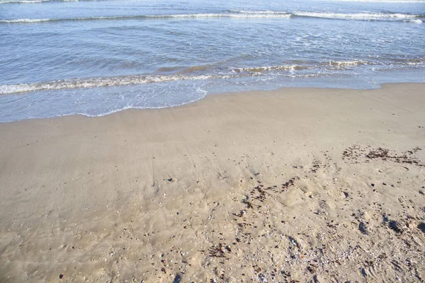 Akdeniz sahilinin arka planında deniz dalgaları olan ilk hattının kum görüntüsü.