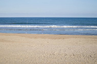 Denize bakan deniz manzarası, hafif dalgaların yükseldiği ve bazı balıkçıların oltalarını bıraktıkları bir günde.