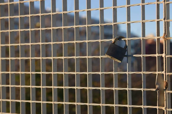 Detail of a padlock that is on a bridge fence during a sunset. Image with copy space
