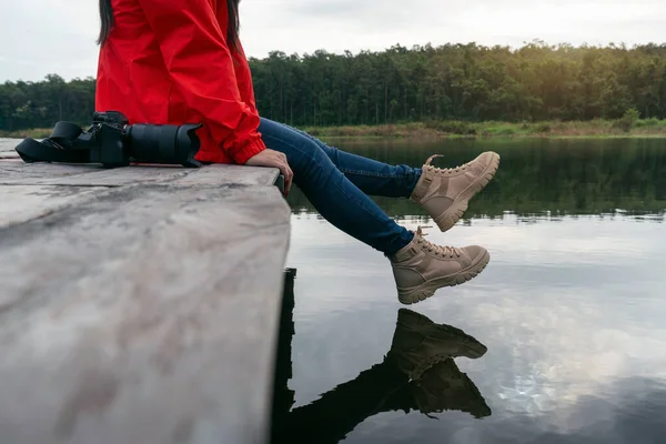 游客在水面附近摆动着脚 女人在湖边放松下来 坐在木制的防波堤上 — 图库照片