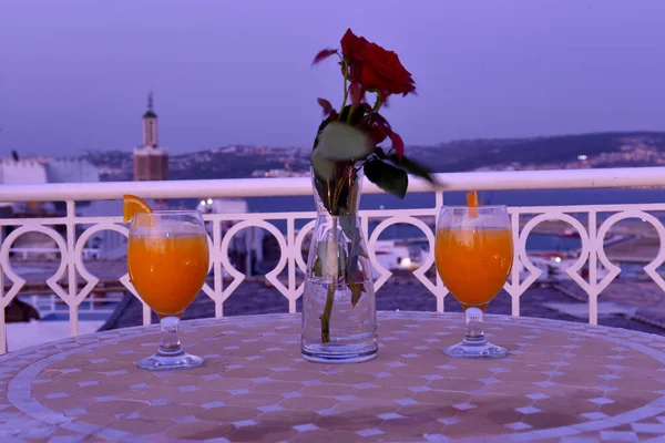 摩洛哥丹吉尔港背景下大理石桌子上的橙汁玻璃杯 — 图库照片