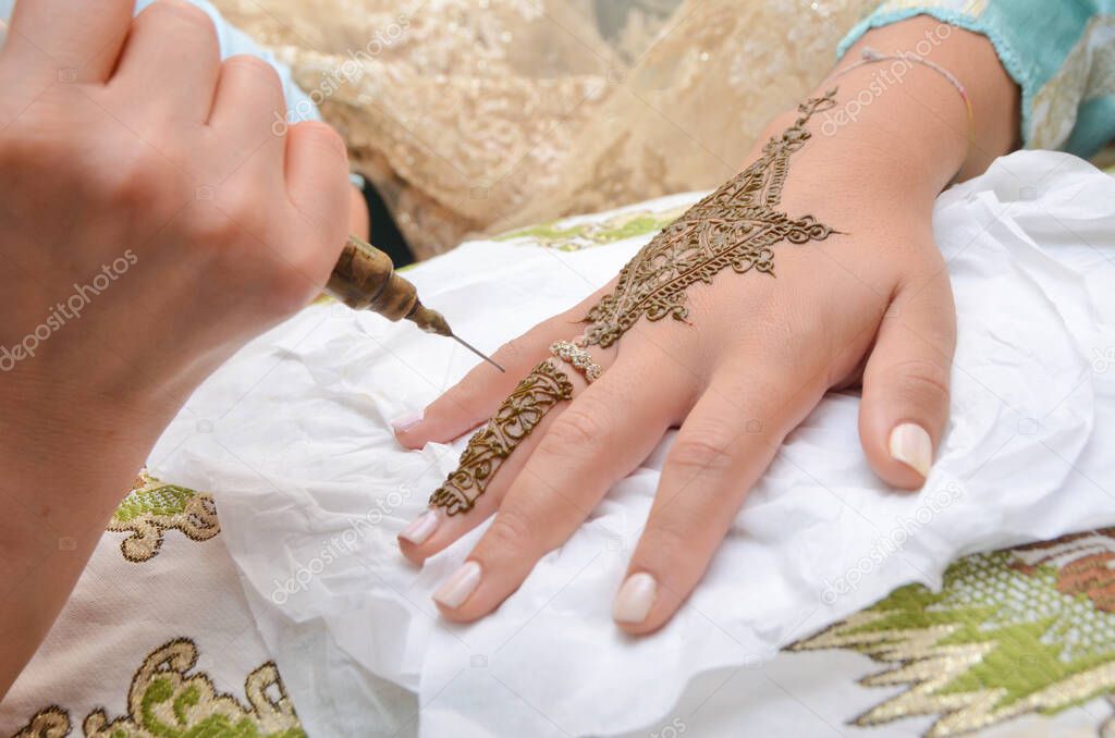 Artist applying henna tattoo on women hands. Mehndi is traditional moroccan decorative art. Close-up, top vie
