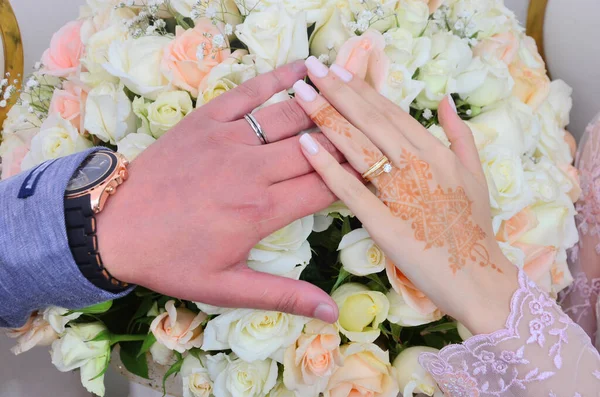 The hand of an Arab bride tattooed with henna holding her groom\'s hand. wedding concept