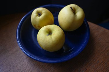 Tahta masadaki sarı elmalar.