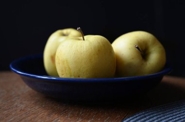 Tahta masadaki sarı elmalar.