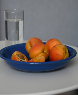 Olgun taze kayısılar ve bir bardak su.