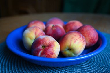 Tahta bir masada, bir kasede taze şeftali.