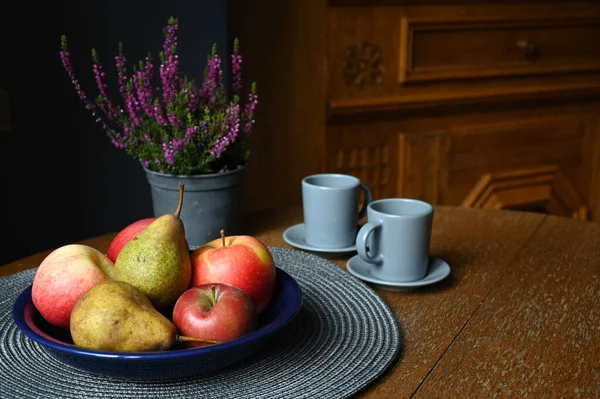 Meyve, seramik kaplar ve çiçeklerle dolu durgun bir hayat