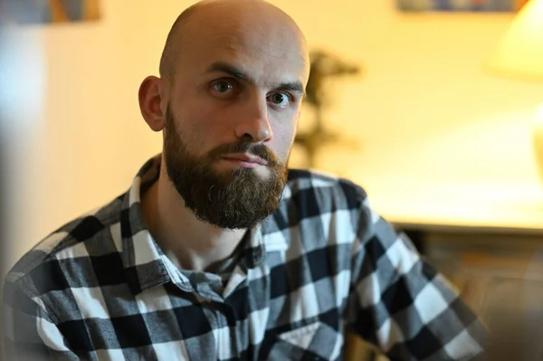 close up portrait of bald bearded man in plaid shirt