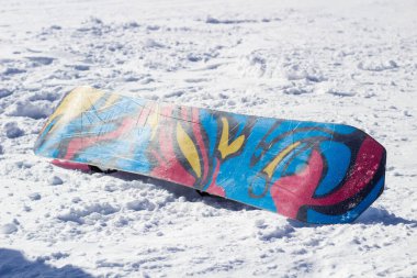 Dağdaki karlı zeminde kar kaykayı. Snowboard baş aşağı duruyor.