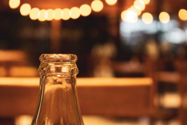 Arka planda Bokeh lambaları olan cam şişeyi kapat. Lokanta içi ışık konsepti. Ziyafet konsepti. Kokain şişesi. Cam kola şişesi. Boş cam şişe..