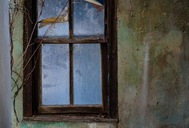 Eski terk edilmiş ev penceresi. İhmal edilmiş ev penceresi arka planı. Binanın etrafını saran yabani otlar. 