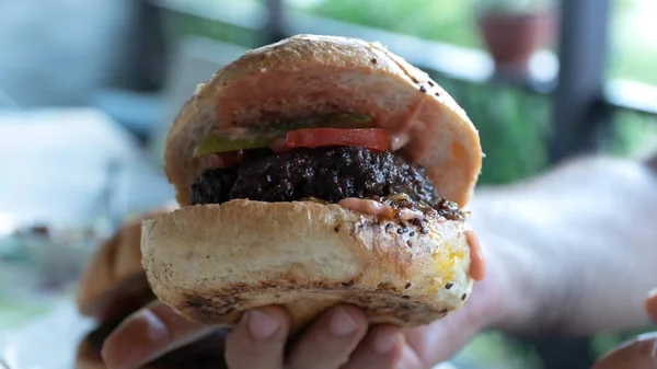 Homemade burger. Male hand holding grilled homemade hamburger. Selective focus included.