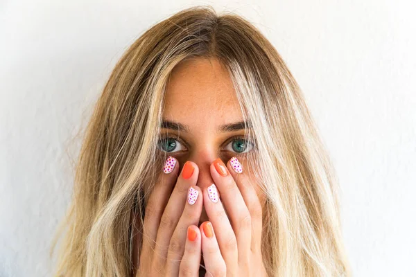 Woman with orange nail art. Portrait of young blonde woman with blue eyes showing her orange colored nail art