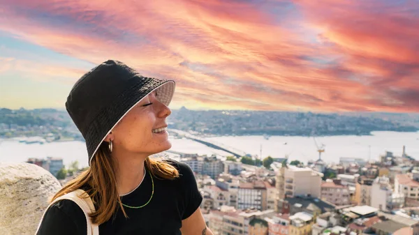 Young tourist woman sightseeing with Istanbul landscape at sunset. Young beautiful woman watching Istanbul from the Galata Tower.