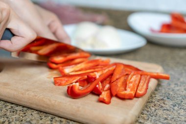 Kadın ellerinin doğrama tahtasına kırmızı biber dilimlediği yakın plan. Sağlıklı beslenme kavramı