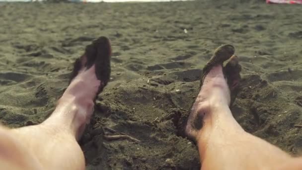 검은 모래 위에서 놀고 있는 발의 근접 사진. 검은 모래 속에서 움직이고 움직이죠.. — 비디오