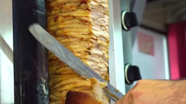 Un cocinero corta carne para hacer shawarma, gyros, kebab doner. Cocinar carne en un pincho — Vídeos de Stock