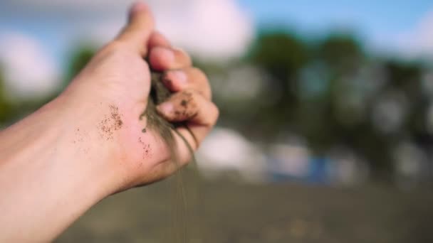 Nahaufnahme Hand ergreift eine Handvoll trockenen Sand und lässt ihn zwischen seine Finger fallen — Stockvideo