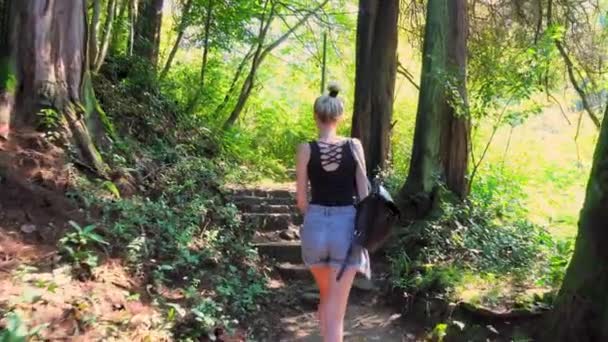 Seorang wanita dengan sandal memanjat tangga batu tua yang bobrok. — Stok Video