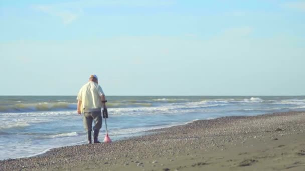 En man med metalldetektor på stranden under en storm. letar efter smycken. — Stockvideo