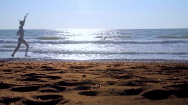 Молодая сексуальная женщина, идущая по волнам на берегу моря. — стоковое видео