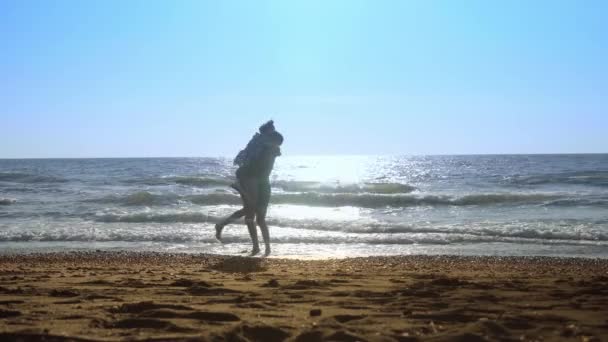 Donna e uomo, corrono l'uno verso l'altro, saltano sulle onde sulla riva del mare. — Video Stock