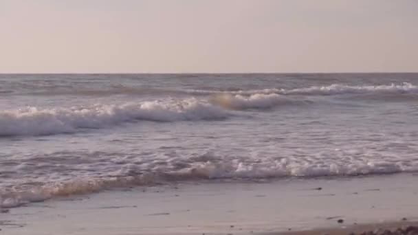 Primer plano de las olas del mar lavando huellas en una playa de arena. — Vídeos de Stock